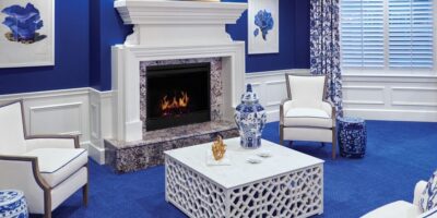 Sitting area with blue carpet, white ottoman and fireplace, and blue decorative accents.