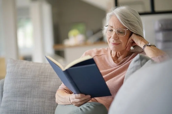  Senior woman reads book at home during COVID-19 quarantine