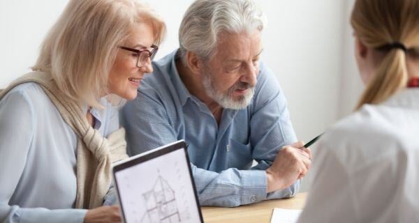 Older couple signing contracts to sell their home.