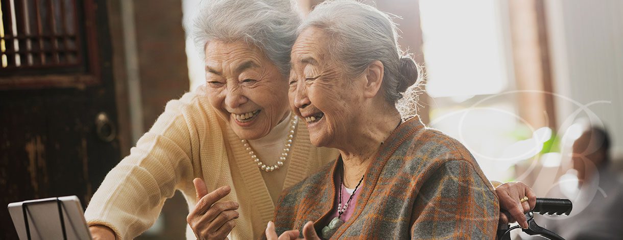 Two senior citizen women looking at a tablet and smiling