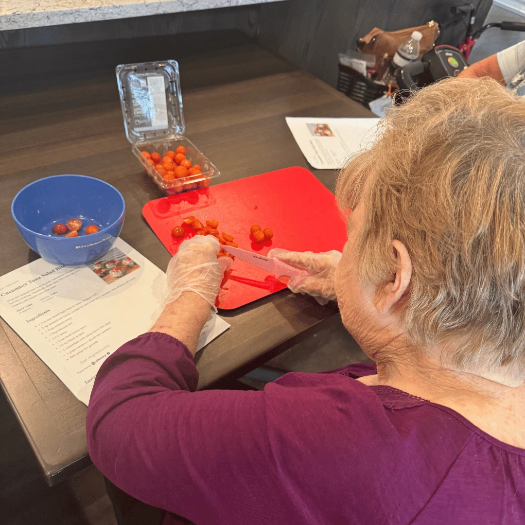A Food Club Member chops tomatoes for Tuna Salad Cucumber Bites in the Bistro at The Bristal at Wayne.