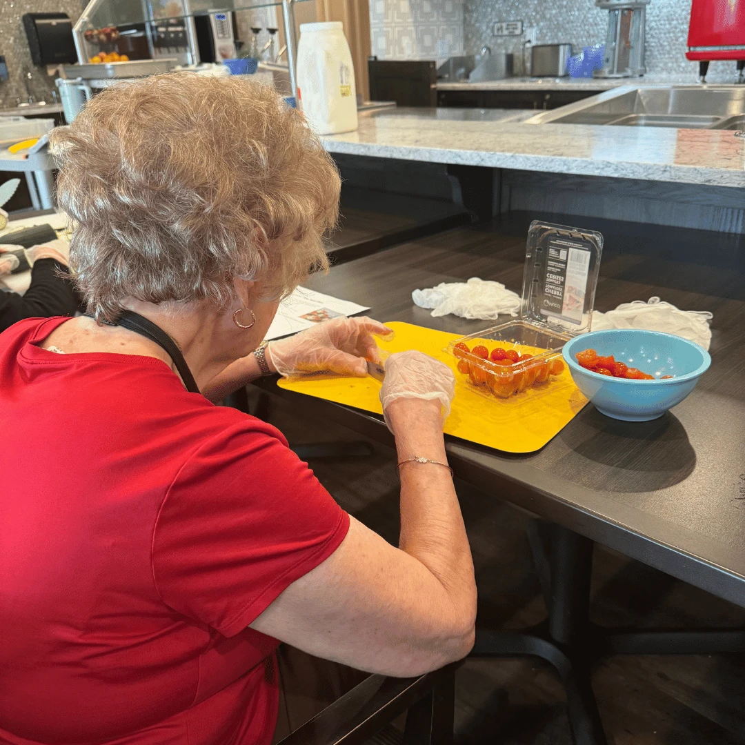 Chopping cherry tomatoes as the garnish for Tuna Salad Cucumber Bites for other residents of The Bristal at Wayne