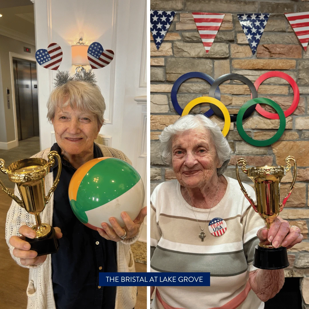 Seniors at The Bristal at Lake Grove posed with trophies under the big rings and the American flag.