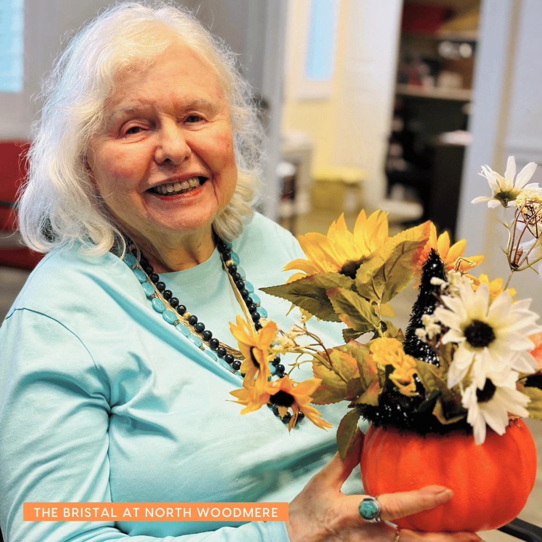 North Woodmere resident smiles while displaying the pumpkin-themed flower arrangement she created for Halloween.
