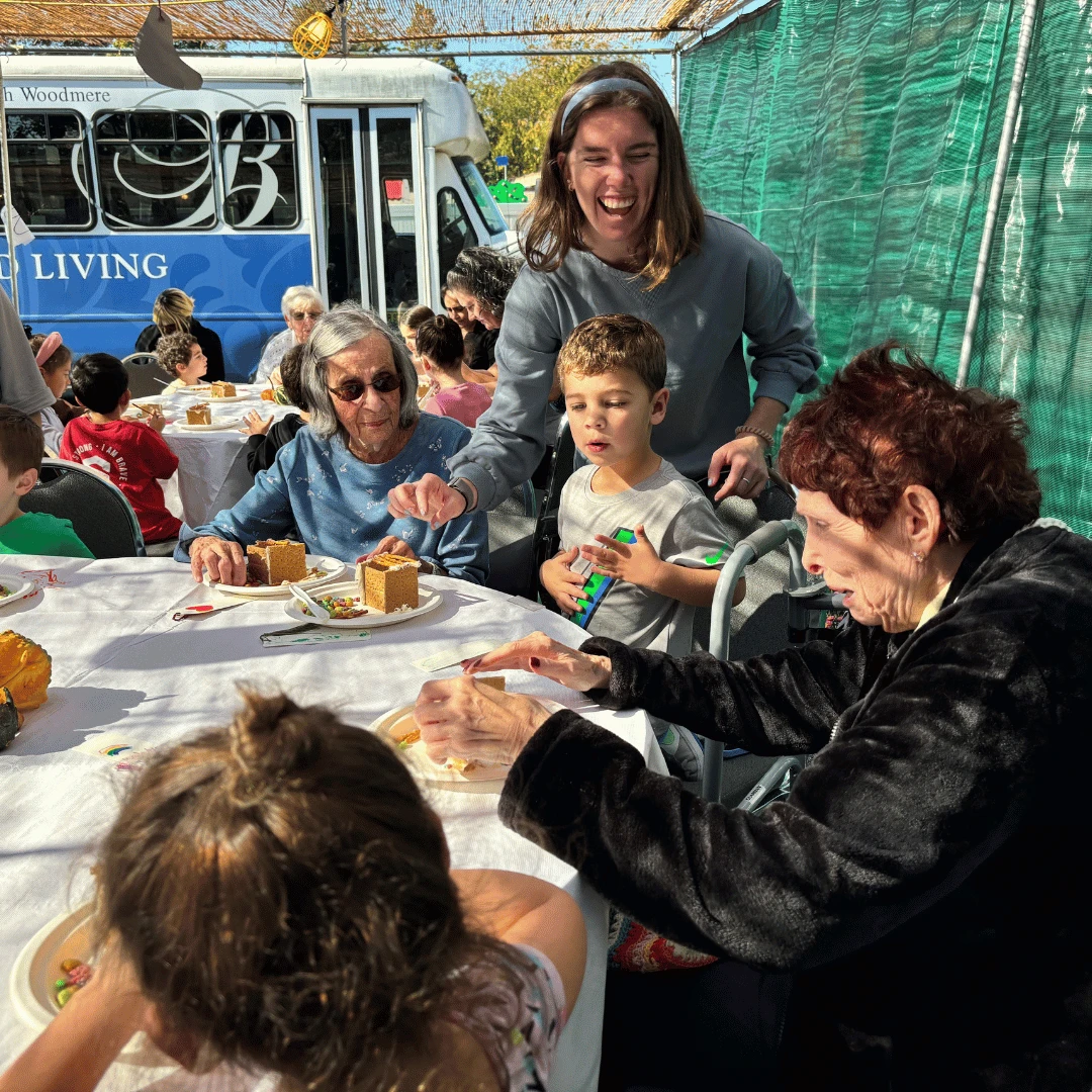 Residents and children build gingerbread sukkahs together for Sukkot