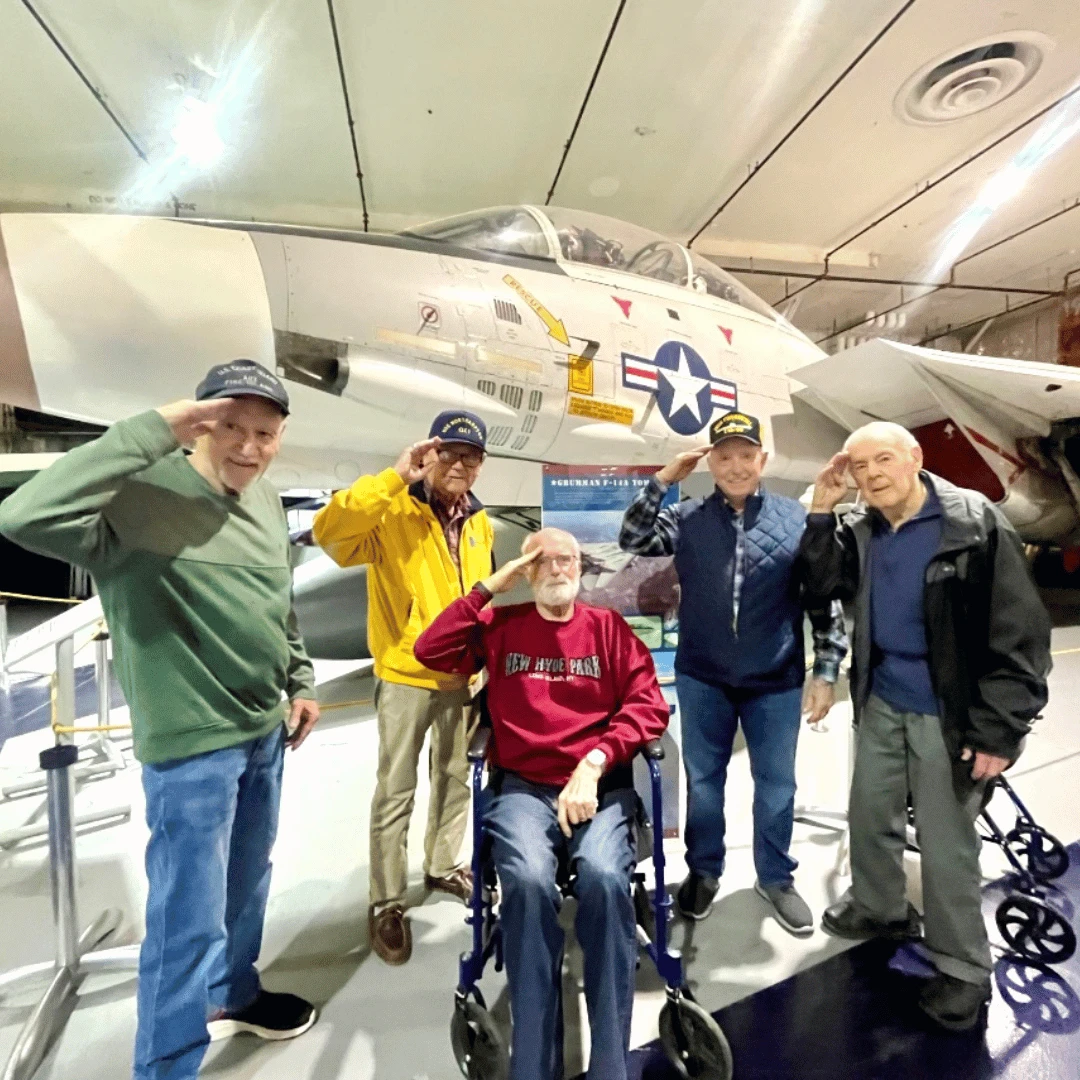 The Men's Club posed for a picture in front of an F-14 Tomcat, created on Long Island by Grumman Aerospace.