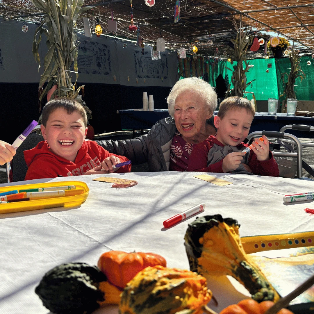 Resident of The Bristal at North Woodmere sits with her great grandchild at a craft table