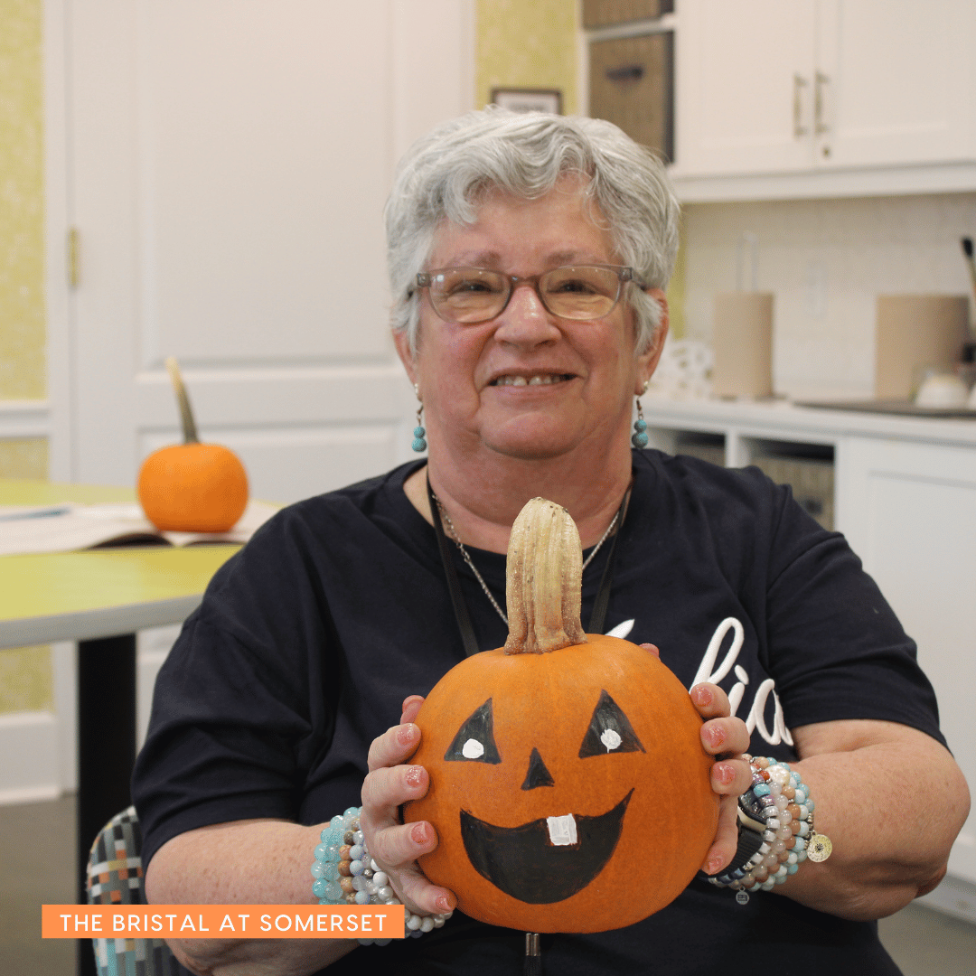 Resident from The Bristal at Somerset shows off a grinning jack-o-lantern she created.