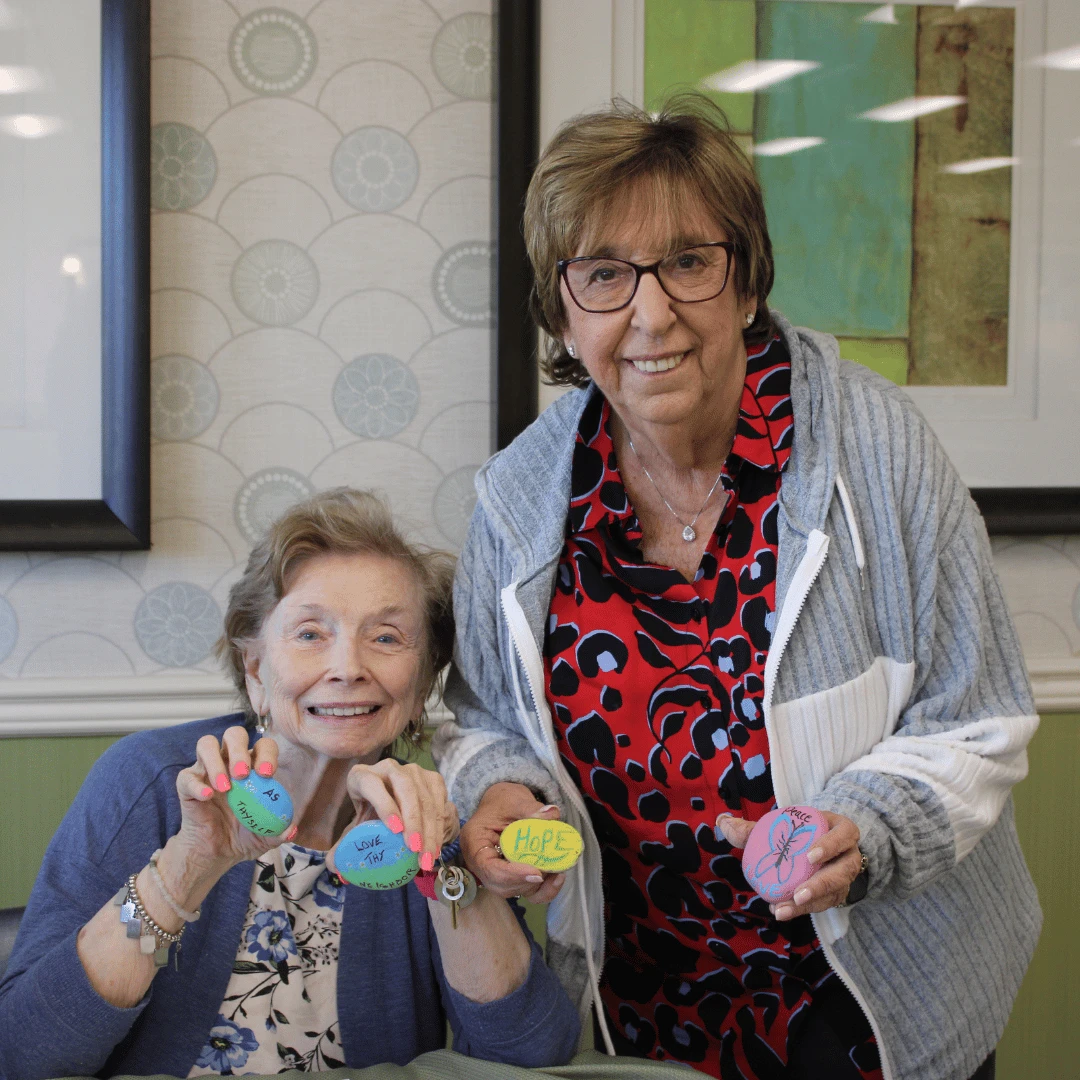 Residents smiling together showing off their brightly colored kindness rocks.