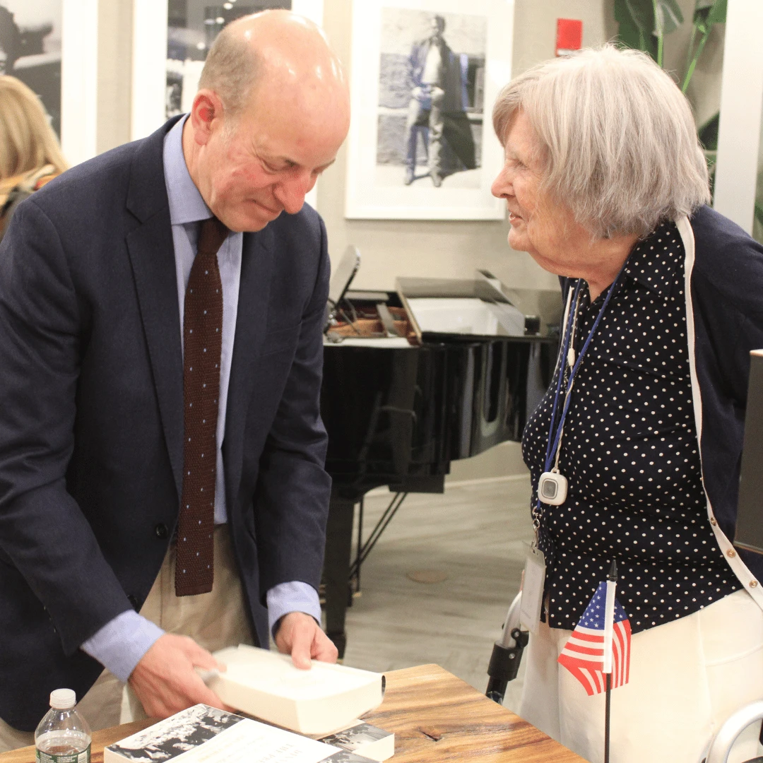 author signs a copy of his book for resident of The Bristal Assisted Living at York Avenue