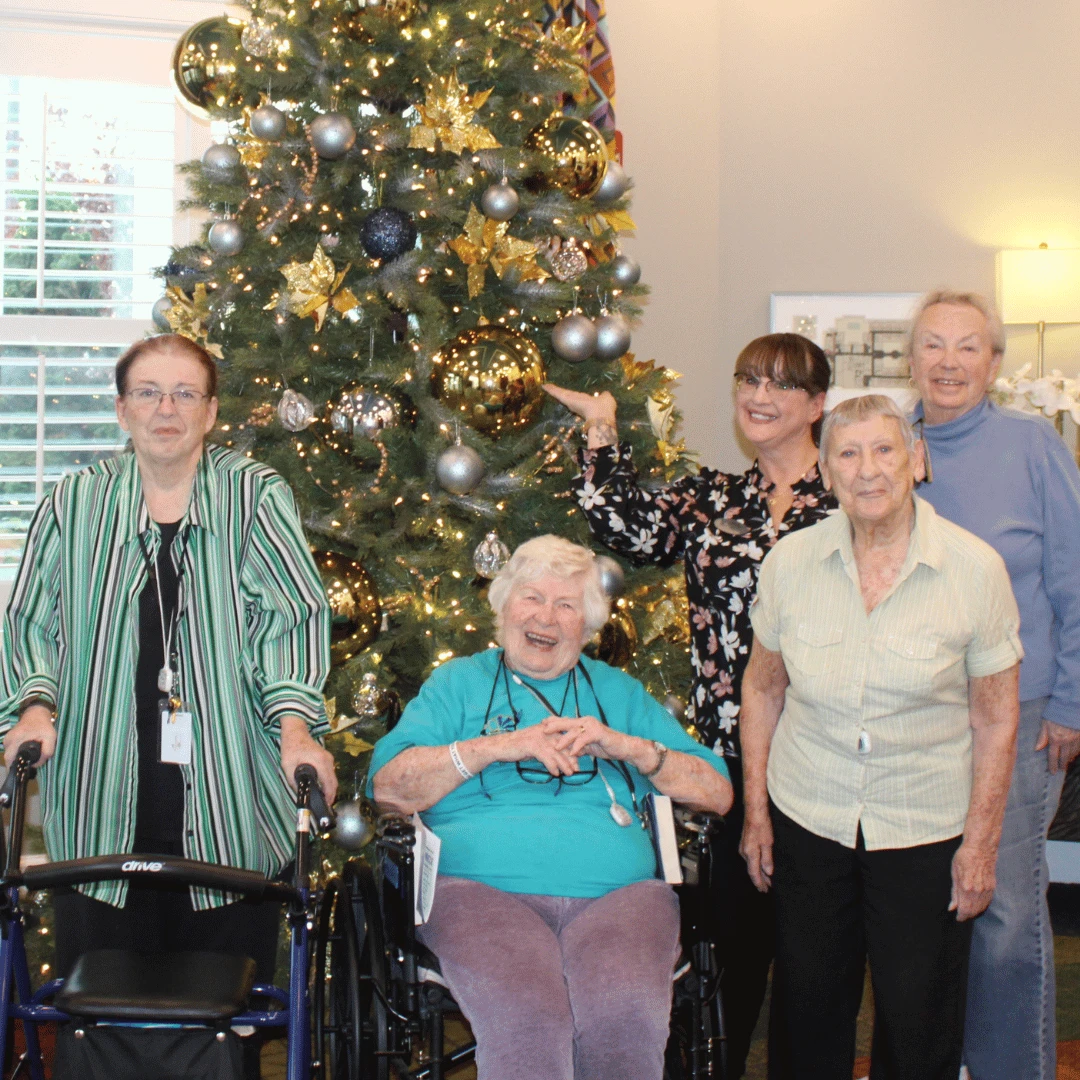 Residents stand smiling before the newly trimmed and lit tree at The Bristal at Somerset