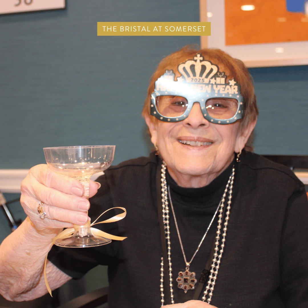 Resident at The Bristal at Somerset wearing New Years galsses and holding a festive cocktail