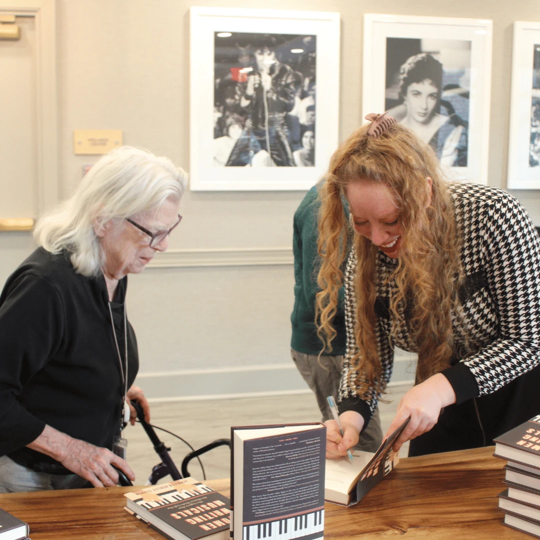 Author Tepper signs a copy of her book for resident.