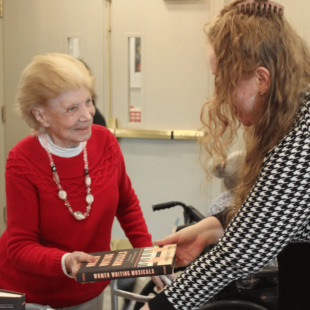 Author hands book to a smiling resident