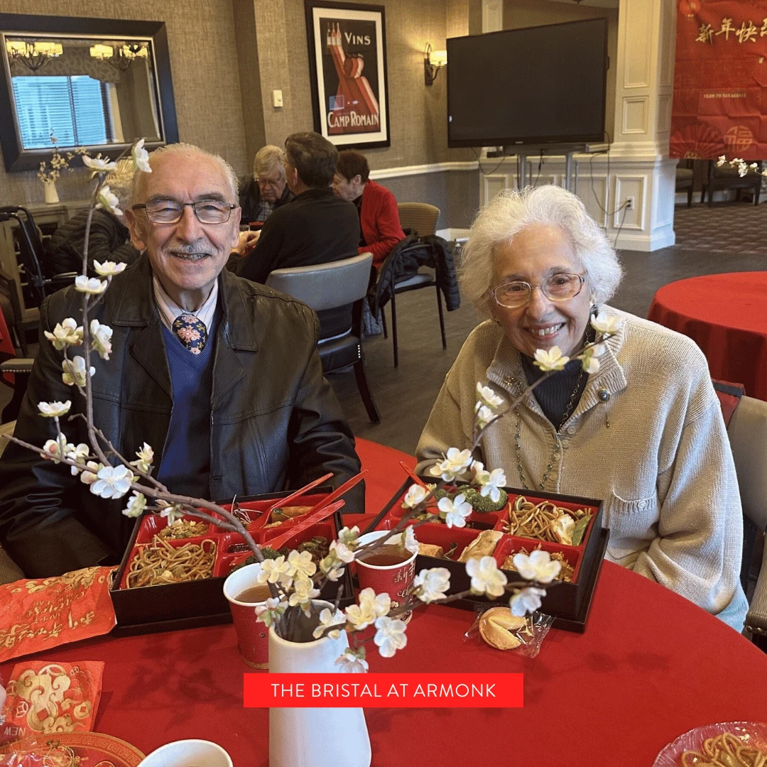 Two residents from The Bristal at Armonk sit at a beautifully adorned table and enjoy a luncheon for Lunar New Year