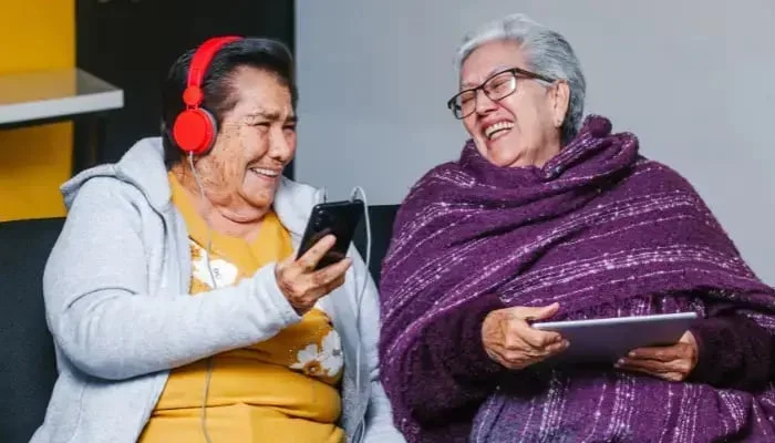 Senior Hispanic women smiling and listening to music together