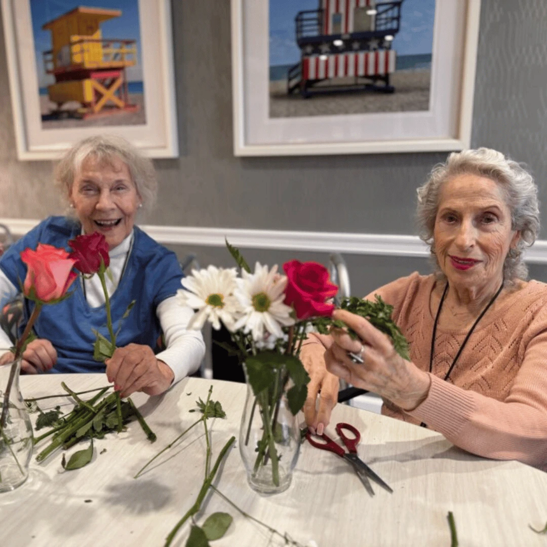 Two resident of The Bristal at Bethpage arrange roses and daisies in a Valentine's Bouquet