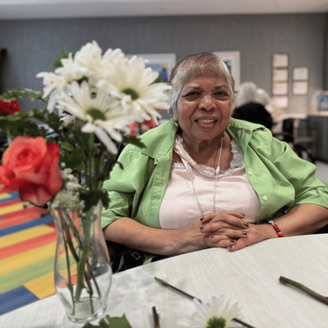 Bethpage resident smiles while posing for photo with bouquet of daisies