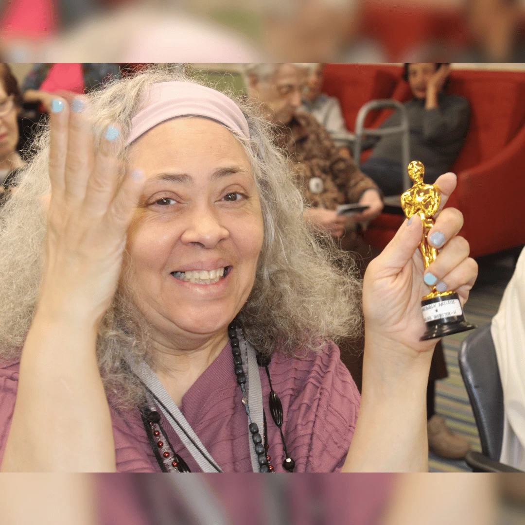 Smiling resident displays her award for the residents of Lynbrook community