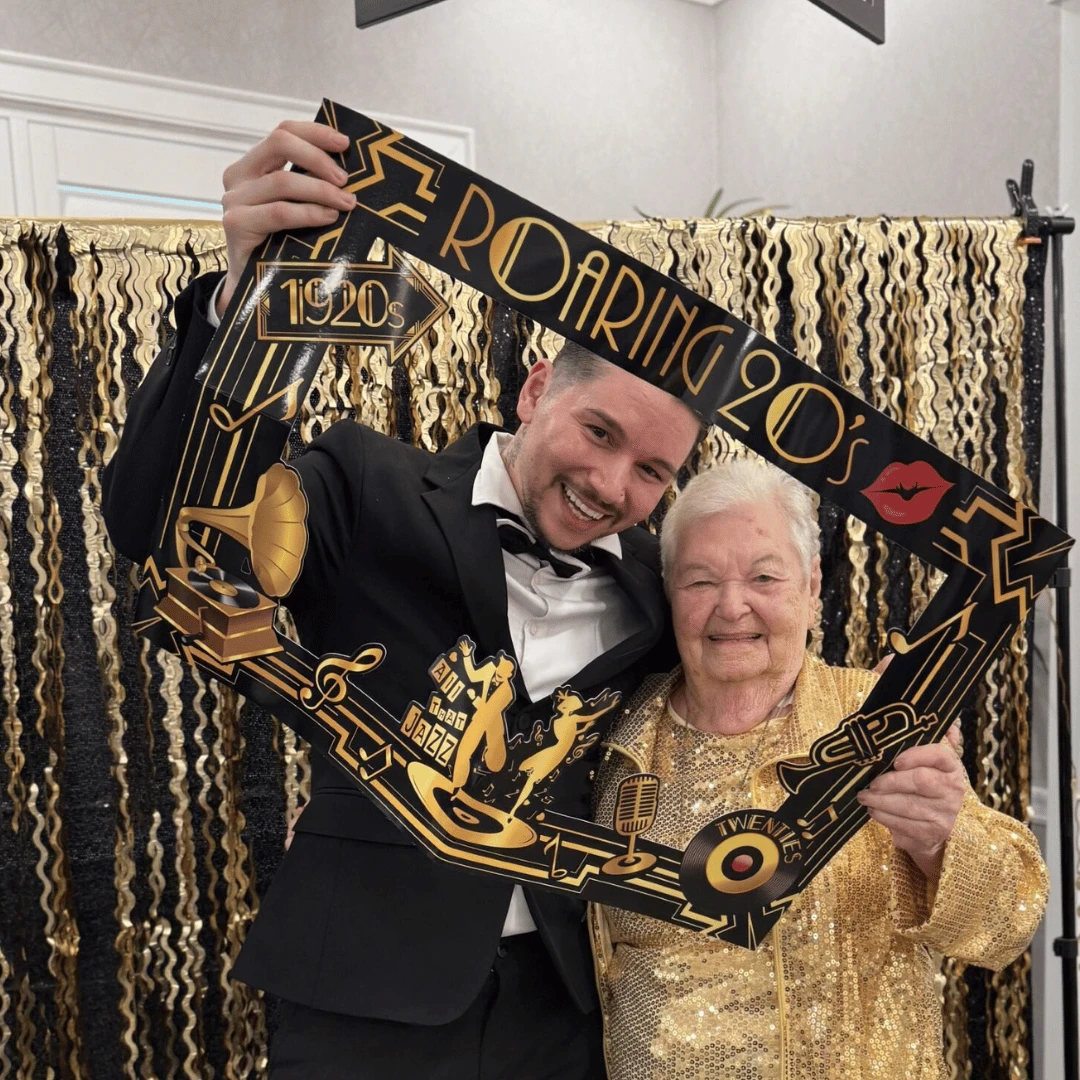 Resident and team members posed for pictures in front of a golden backdrop at The Bristal Assisted Living