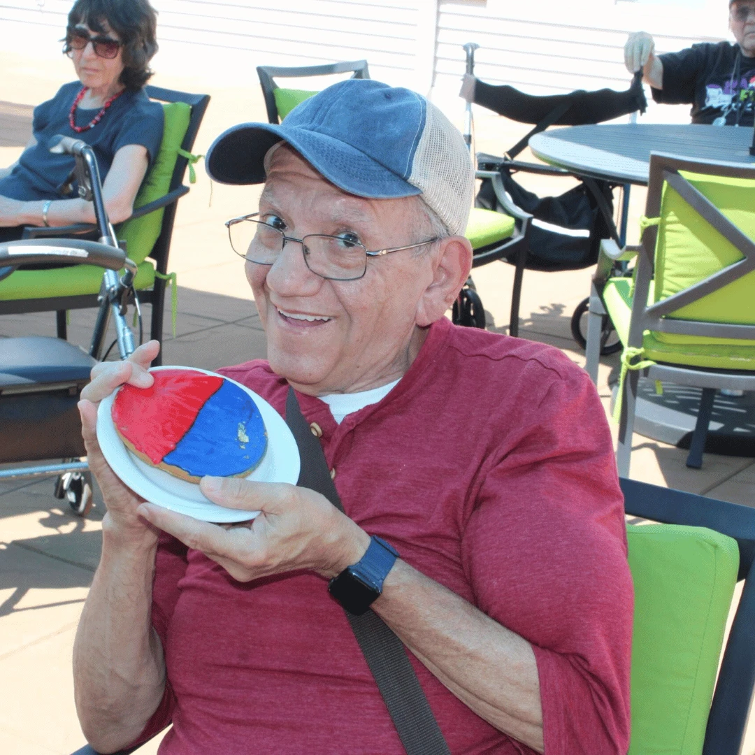A resident from The Bristal at Somerset holds up a red and blue cookie while wearing red white and blue to celebrate Independence Day
