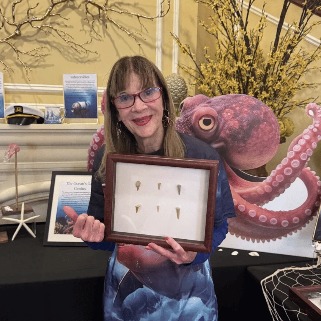 Resident from The Bristal at Lake Grove holds a shark teeth exhibit surrounded by other museum exhibits