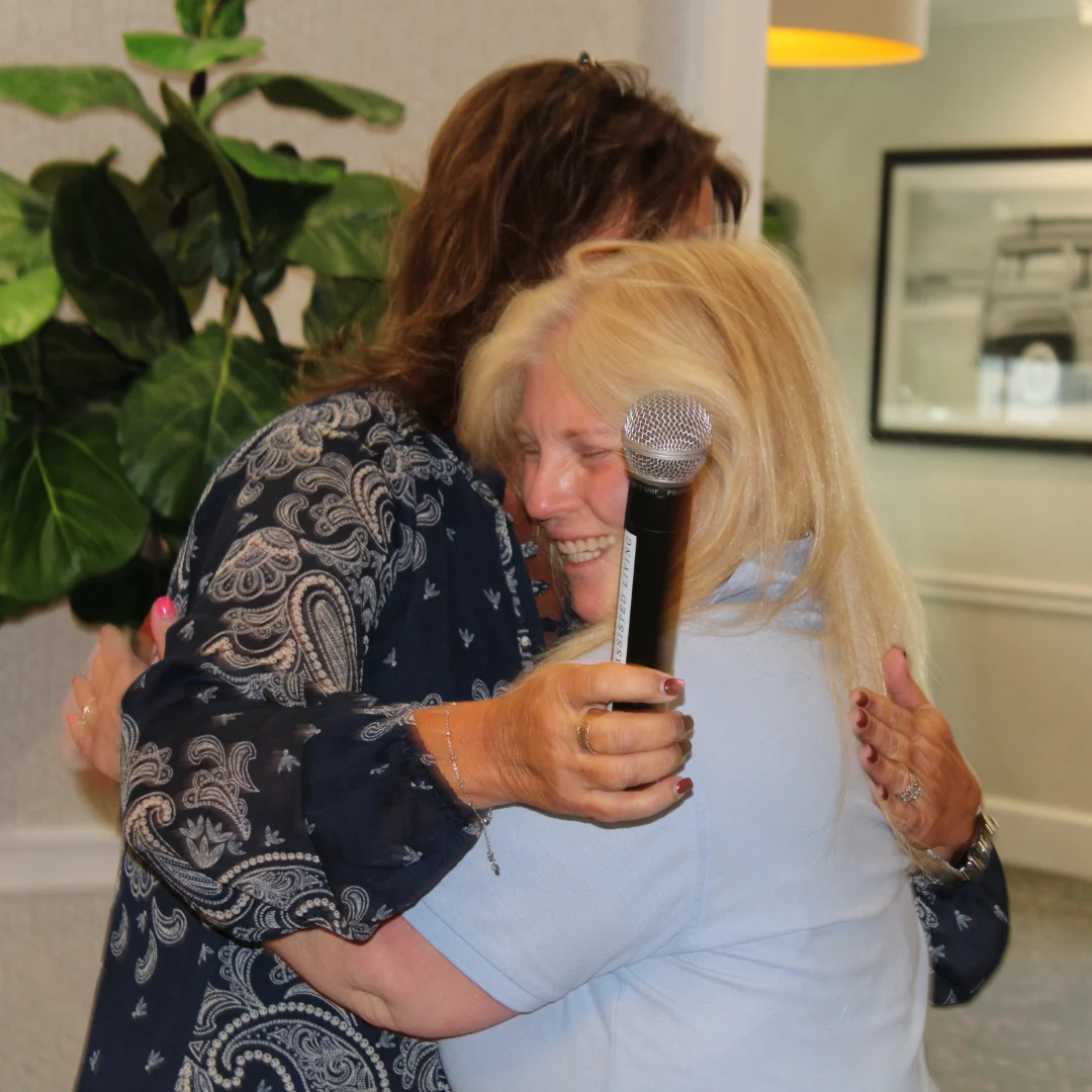 Mount Sinai Executive Director Karen embraces Lifestyle Coordinator Pamela after awarding her the recognition