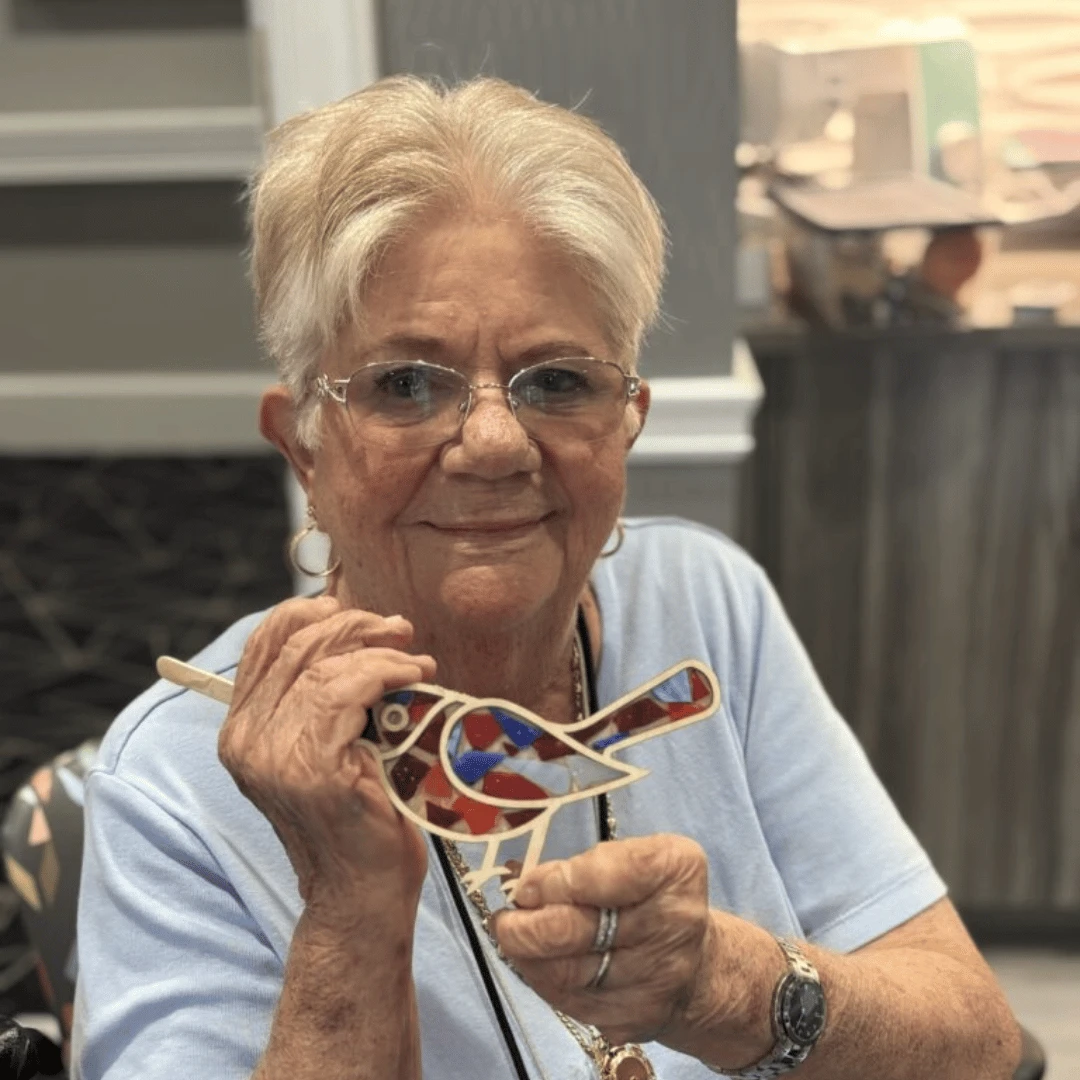 Bethpage resident holds up a bird mosaic keepsake of the day's immersive program