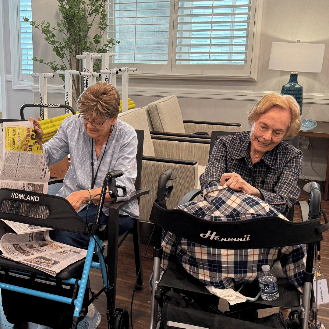 Two residents of The Bristal at Sayville stuff their scarecrows with newspaper