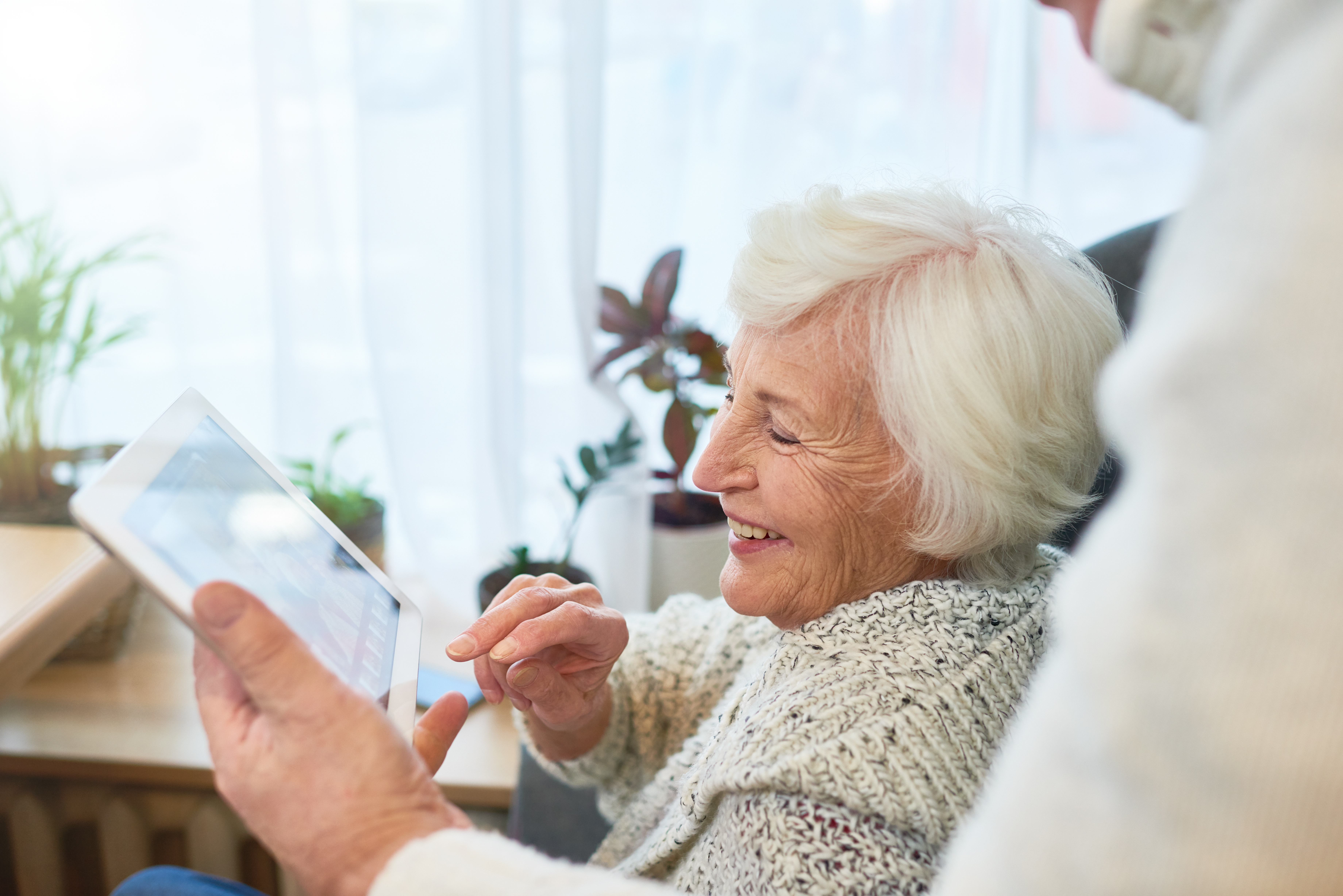 Resident of The Bristal smiling while a team member assists her using a tablet