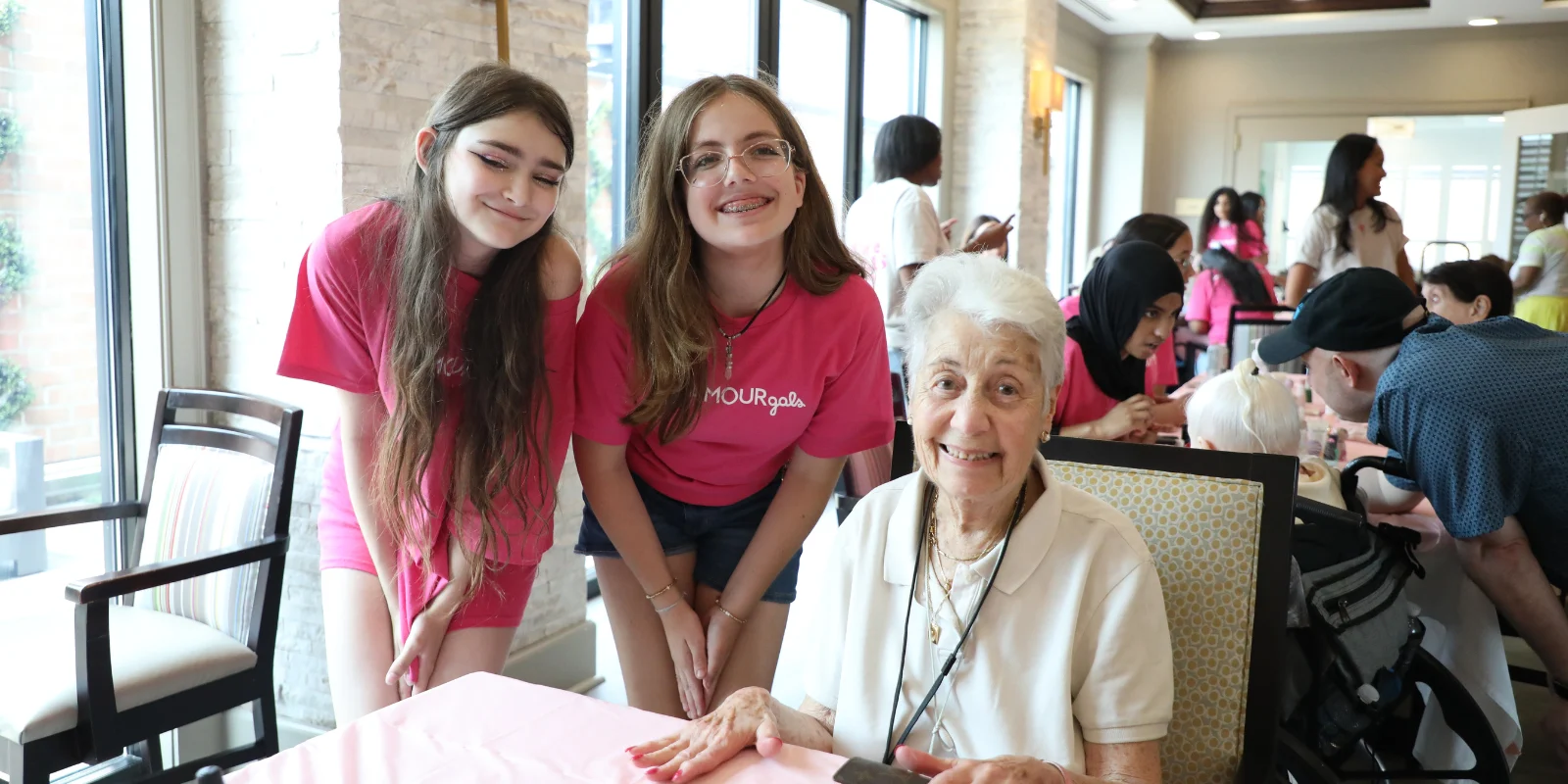 Two GlamourGals volunteers pose for pictures with resident of The Bristal